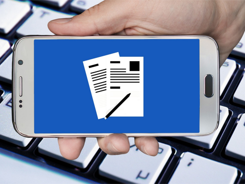 Hand mit Smartphone auf dem Dokumente sichtbar sind